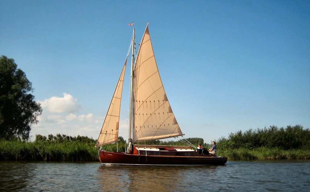 The traditional wooden Lullaby class cabin yacht Lucent sails the Norfolk Broads