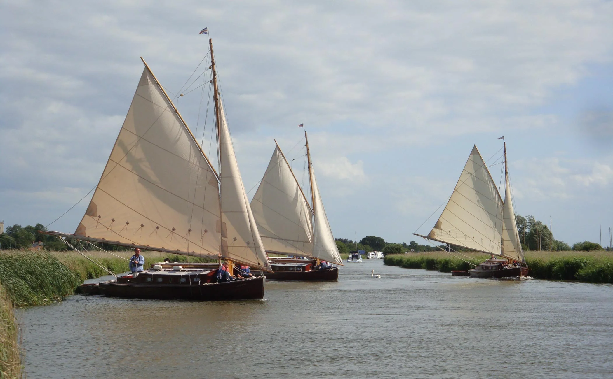 Three traditional wooden cabin yachts sailing on the Norfolk Broads