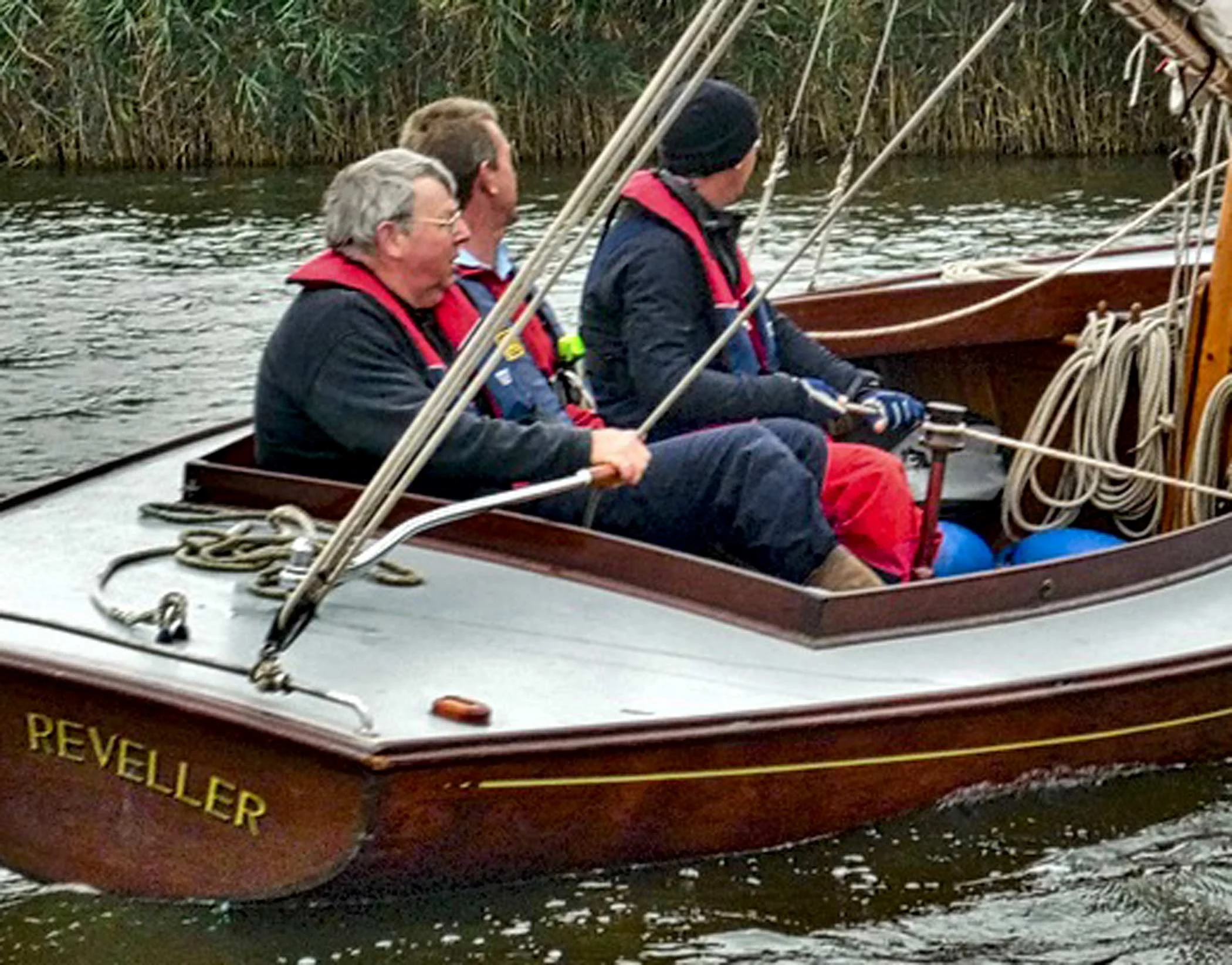 A group learning to sail on a traditional wooden half-decker on the Norfolk Broads.